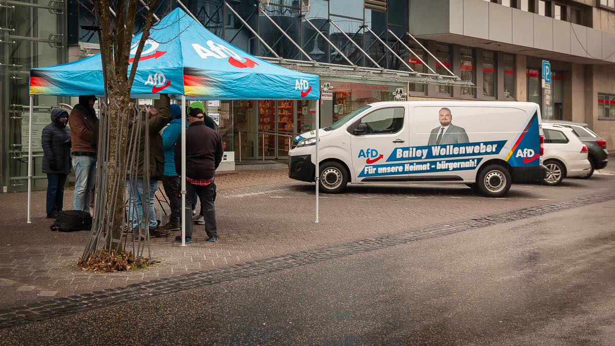 Infostand der AfD Westerwald in Bad Marienberg bei Eisregen und starkem Wind: Parteimitglieder stehen unter einem blauen AfD-Pavillon, daneben ein AfD-Infomobil in der Innenstadt.